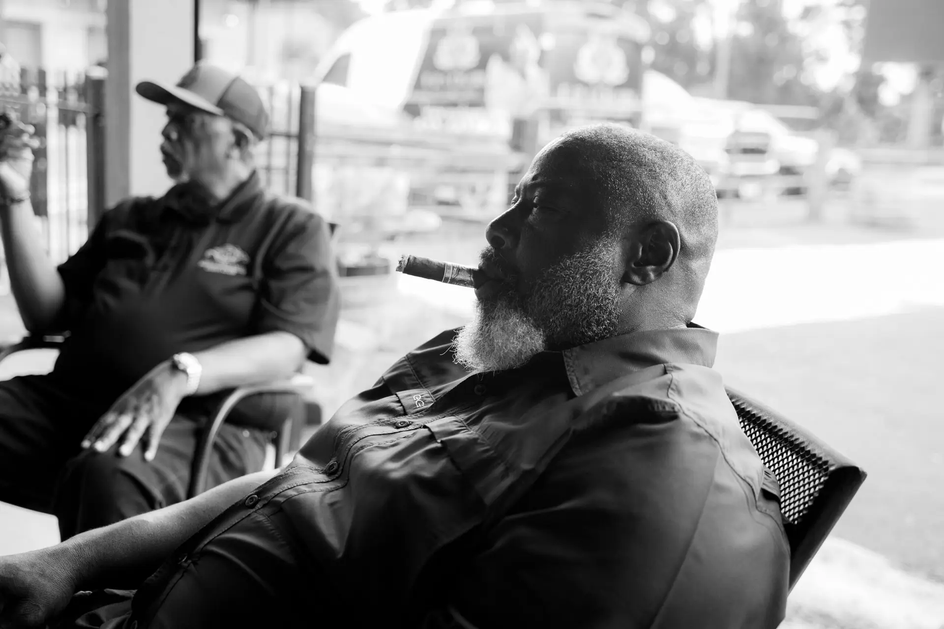 Man smoking a cigar in the covered patio at Ember & Vine